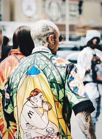 REAR VIEW OF MAN WITH MULTI COLORED UMBRELLAS