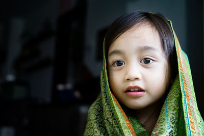 Portrait of cute asian toddler, kid, girl wearing traditional songket shawl.