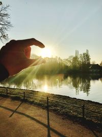 Close-up of hand holding sun during sunset