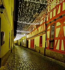 Footpath amidst buildings in city at night