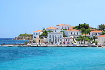 Buildings by sea against clear sky