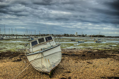 Sailboats moored on beach against sky