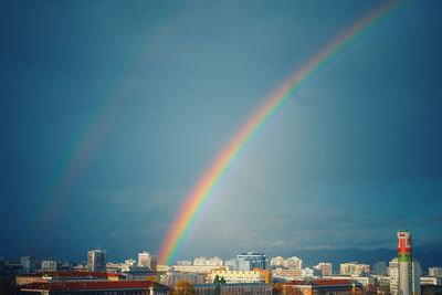 Rainbow over buildings in city against sky