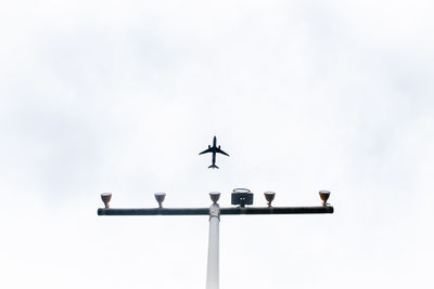 Low angle view of silhouette airplane flying against sky