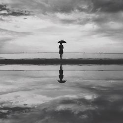 Woman under umbrella on shore