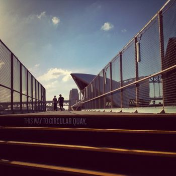 Couple walking on footpath against sydney opera house