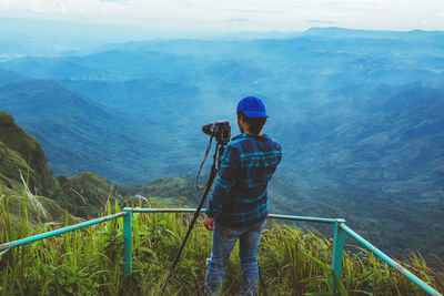 Rear view of man photographing on mountain