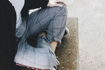 Low section of woman sitting on bench in city