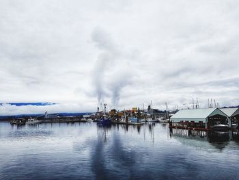 Panoramic view of factory by sea against sky