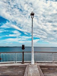 Street light by sea against sky