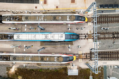 Aerial view directly above high speed passenger trains in a yard with overhead electric wires