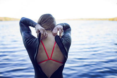 Rear view of swimmer wearing wetsuit at lakeshore