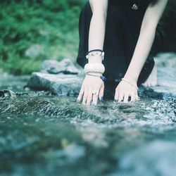 Low section of woman crouching on rock