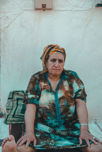 Portrait of woman sitting against wall