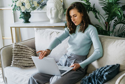 Beautiful woman on the couch working on a laptop.