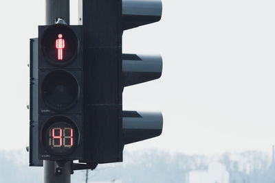 Close-up of illuminated traffic signal against sky