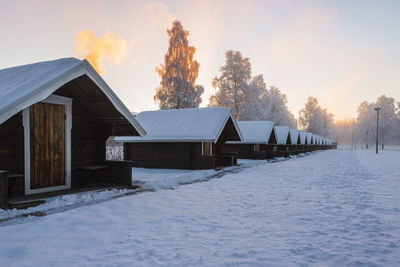 Row of snow covered cabins at sunrise