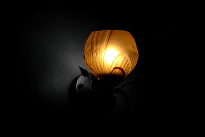 Close-up of illuminated light bulb over black background