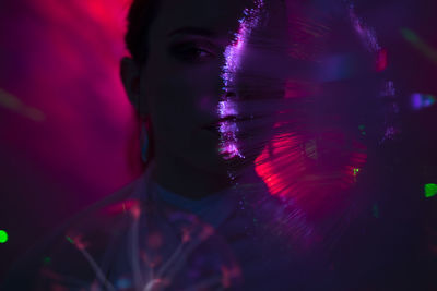 Portrait of beautiful young woman against illuminated background