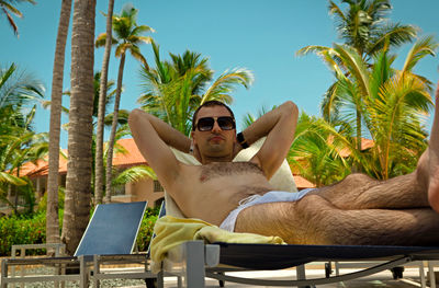 Young man with sunglasses against palm trees