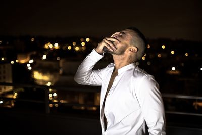 Mature man with head in hand standing outdoors at night