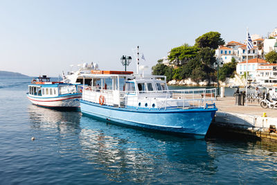 Boats moored at harbor against clear sky