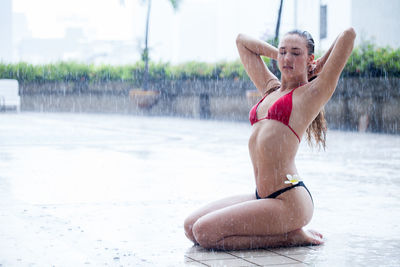 Young woman in bikini sitting outdoors during rainy season