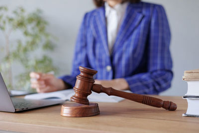 Midsection of lawyer holding gavel on table