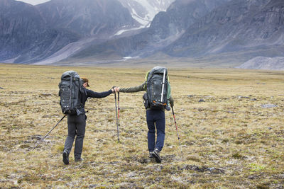 Two backpackers (friends) fist bump during journey across arctic pass
