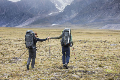 Rear view of men on field against mountain