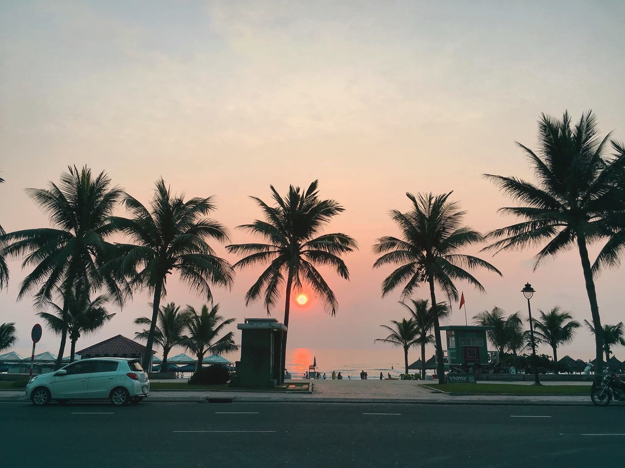 PALM TREES ON ROAD AGAINST SKY DURING SUNSET