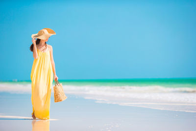 Full length of woman standing on beach against sky