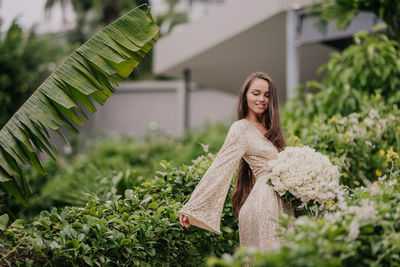 Young girl in a golden dress with a bouquet of white roses