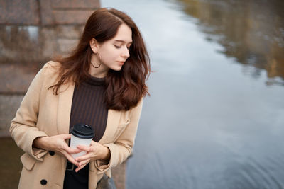 Young woman looking at river while standing by railing