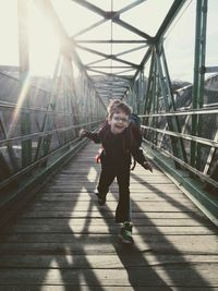 Portrait of smiling boy running on footbridge