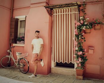 Man standing by bicycle against wall