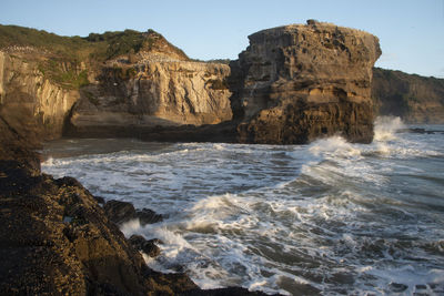 Scenic view of rocks on beach against clear sky