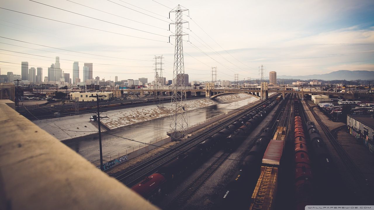 railroad track, power line, building exterior, transportation, city, built structure, electricity pylon, architecture, rail transportation, cable, sky, electricity, connection, power supply, public transportation, power cable, railroad station, railroad station platform, railway track, diminishing perspective