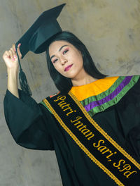 Portrait of a smiling young woman standing against wall