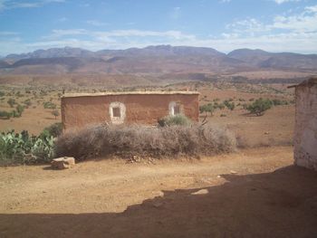 House on field by mountains against sky