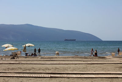 People at beach against clear sky