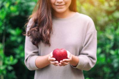 Midsection of woman holding apple