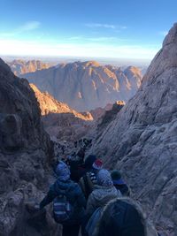 Rear view of people on rock by mountains against sky