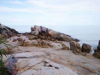 Rocks on shore by sea against sky
