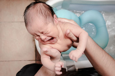 A baby is crying while the father to give him a bath
