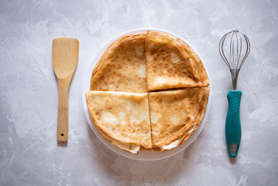 Top view of pancakes on a plate and wooden whisk as batter or dough ingredients 