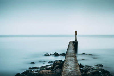 Close-up of wooden post by sea against clear sky