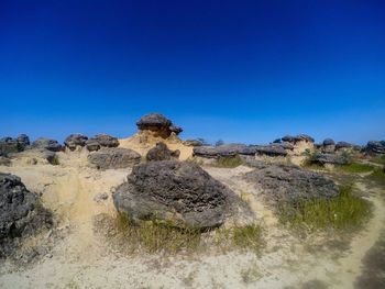 Panoramic shot of rocks on land against clear blue sky