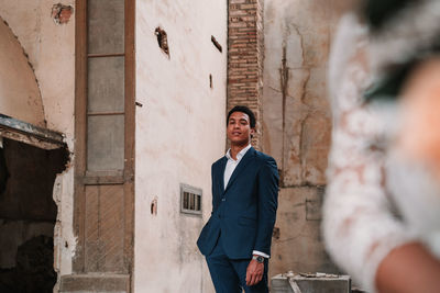 Young man standing against wall of building