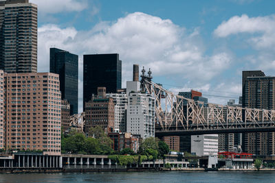 Modern buildings by river against sky in city